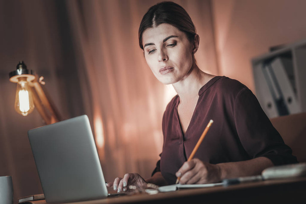 Earnest female freelancer taking notes - Фото, изображение