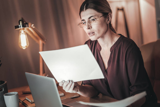 Attentive female freelancer examining documents - Photo, image