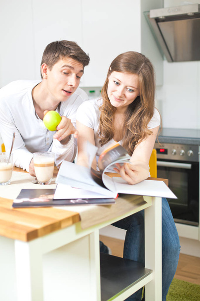 Happy young couple reading book during breakfast - Photo, image
