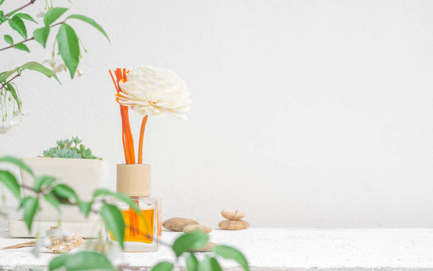 Aromatic reed freshener, Fragrance Diffuser Set of bottle with aroma sticks (reed diffusers) on white wall background and blurred green plant foreground. - Photo, Image
