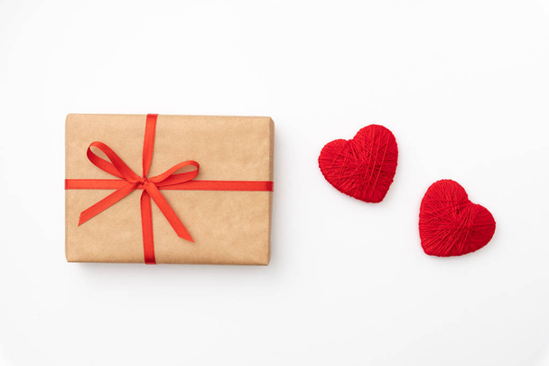Decoración San Valentín en la mesa vista superior de fondo. Composición plana de forma roja corazón y caja de regalo de papel artesanal con cinta sobre fondo blanco para maquillar su diseño. Concepto de día de amor
 - Foto, imagen