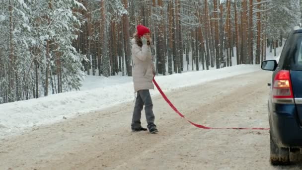 vrouw met een stro auto op de weg in de winter - Video