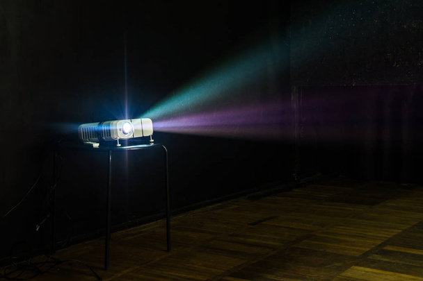 Primer plano del proyector multimedia con rayos de luz de colores proyectados en la pantalla
 - Foto, Imagen