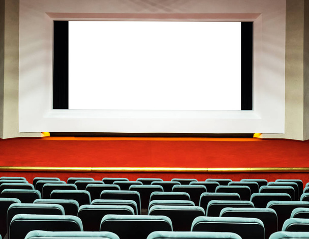 Empty rows of comfortable seats with big screen with white clipping path in cinema or theater  - Photo, Image