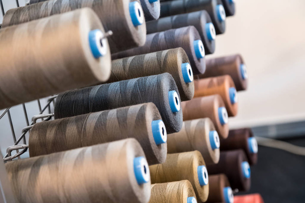 衣料品業界で使用されるカラフルな刺繍糸スプール、多色糸ロールの行、市場で販売されている縫製材料 - 写真・画像
