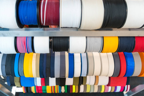 Bunte Stickgarnspule für die Bekleidungsindustrie, Reihe von bunten Garnrollen, Nähmaterialien, die auf dem Markt verkauft werden - Foto, Bild