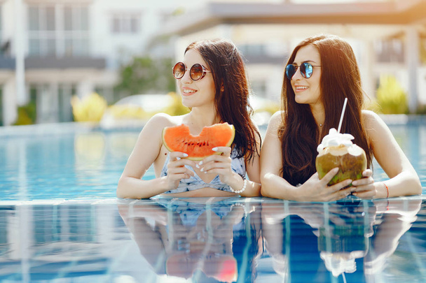 two girls having fruit by the pool - Фото, изображение