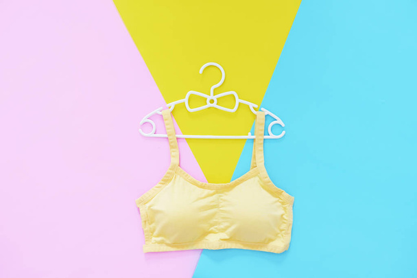Top View of Sportswear on White Hanger. Women is Yellow Sports Bra Isolated on Pink & Yellow and Blue Color Pastel. Beautiful Sport Accessories & Fashion, Healthy. Sport Clothes on Colorful Background. - Fotó, kép