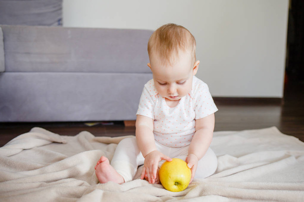 Baby girl sitting on the floor with yellow apple. Feeding up and first food concept - 写真・画像