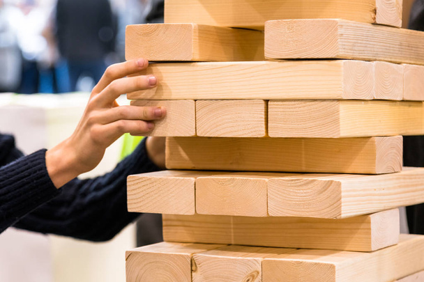 Tower block, l'uomo prende una parte in legno della torre di legno. Pianificazione, rischio e strategia nel concetto di business
 - Foto, immagini