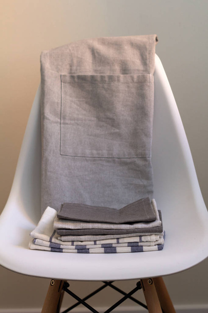 stos, ręczniki kuchenne, serwetki i fartuch na krześle biały - Zdjęcie, obraz