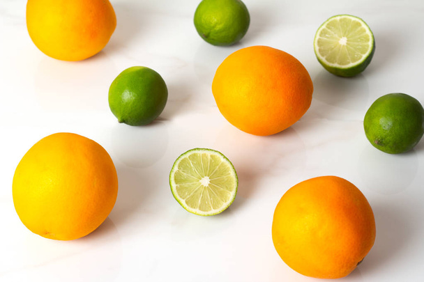 kalk en sinaasappelen boven op een witte achtergrond weergeven - Foto, afbeelding