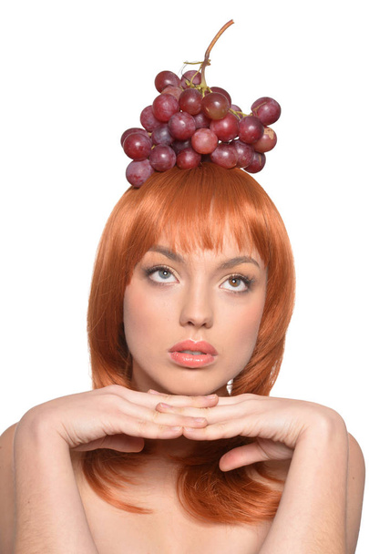 Portrait of a redhead young woman with red grapes on head isolated on white background - 写真・画像