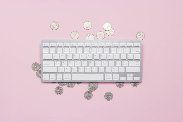 Keyboard and coins on a pink background. Dollar sign The concept of income on the Internet, remote work. Flat lay, top view - 写真・画像
