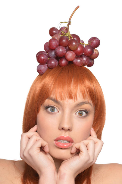 Portrait of a redhead young woman with red grapes on head isolated on white background - Φωτογραφία, εικόνα