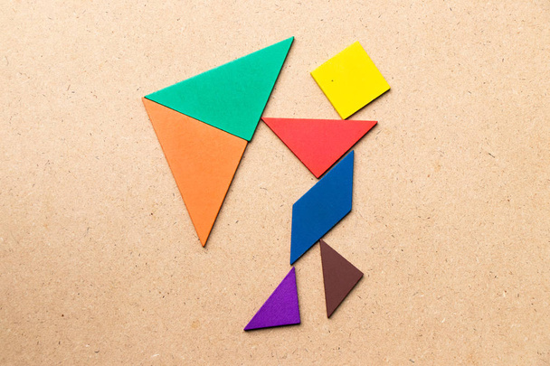 Color tangram puzzle in man hold umbrella shape on wood background (Concept as business has the crisis or problem) - Photo, Image