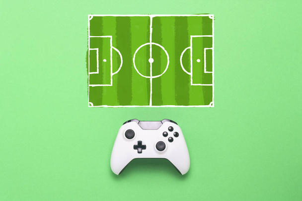 Λευκό gamepad σε πράσινο φόντο. Πρόσθεσε ένα καθεστώς ποδόσφαιρο πεδίο. Τακτική του παιχνιδιού. Έννοια παιχνίδι του ποδοσφαίρου στην κονσόλα, παιχνίδια στον υπολογιστή. Επίπεδη lay, κορυφαία προβολή - Φωτογραφία, εικόνα