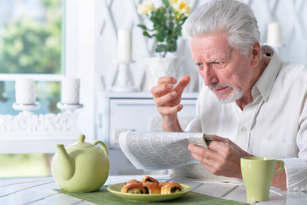 Emotional senior man  reading newspaper at home  - Zdjęcie, obraz