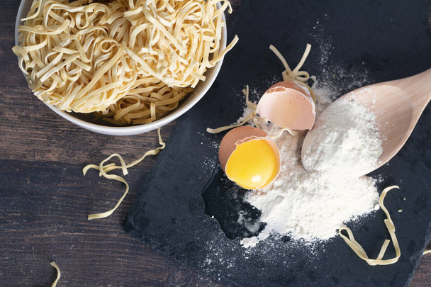 broken egg, flour and egg noodles on a wooden tabl - Foto, Imagen