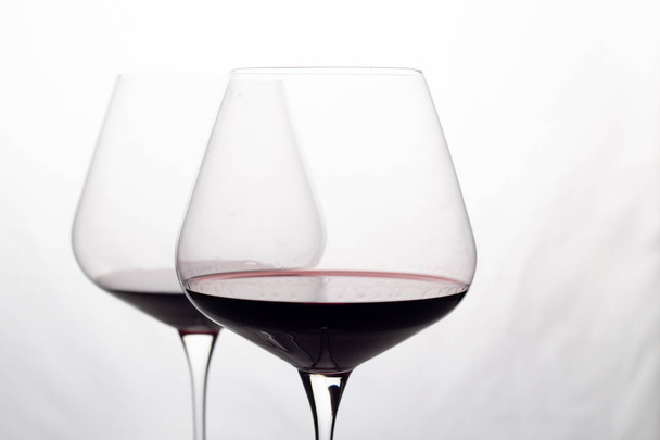 kaksi lasillista punaviiniä valkoisella pohjalla lähikuva
 - Valokuva, kuva