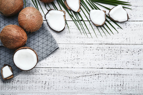 Ripe coconuts with napkin and palm leafs on wooden table - Fotografie, Obrázek