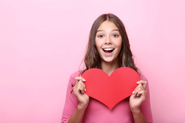 Young girl holding red paper heart on pink background - Fotografie, Obrázek