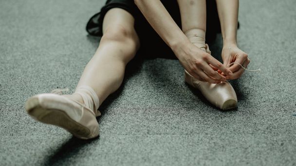 Ballerina putting on pointe shoes and preparing to training  - Fotó, kép