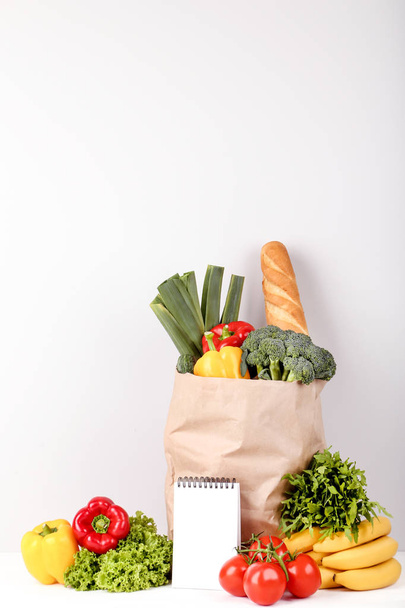 Grocery shopping bag with food and blank notepad on grey background - Zdjęcie, obraz