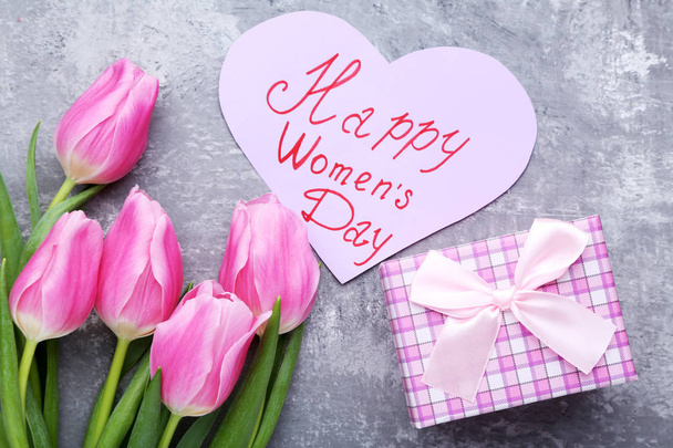 Bouquet of tulips with gift box and paper with inscription Happy Women Day - 写真・画像