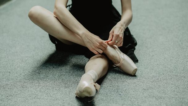 Ballerina putting on pointe shoes and preparing to training  - Фото, изображение