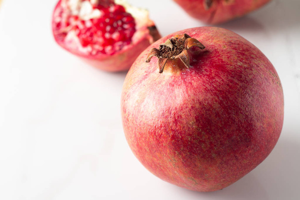 rode granaatappel en granaatappel zaden op een witte marmeren achtergrond close-up - Foto, afbeelding