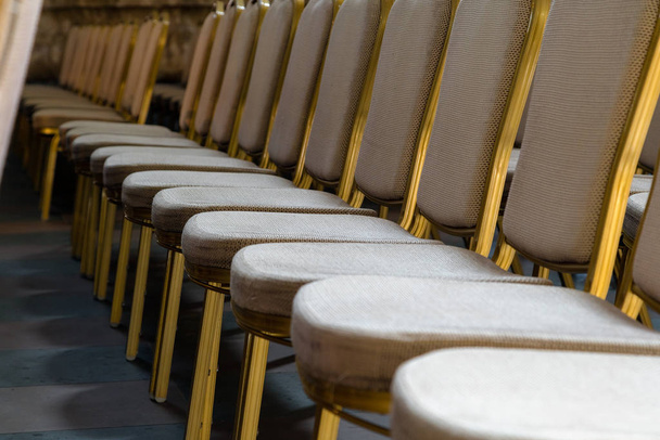 Filas de sillas tradicionales de madera dura con cojín suave y borde dorado para reuniones formales, conferencias, conferencias, ceremonias de graduación
  - Foto, Imagen