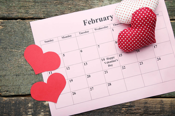 Red hearts with february calendar on wooden table - Fotó, kép