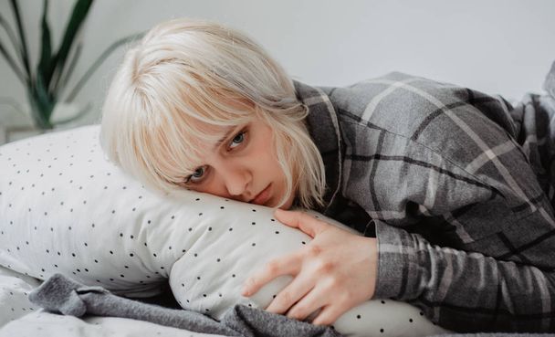 Stressed blonde young woman lying in bad - Photo, Image