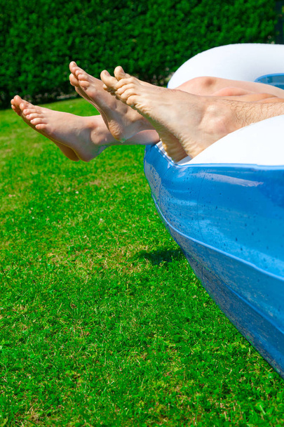 cropped shot of legs of people lying in garden pool - Foto, Imagem
