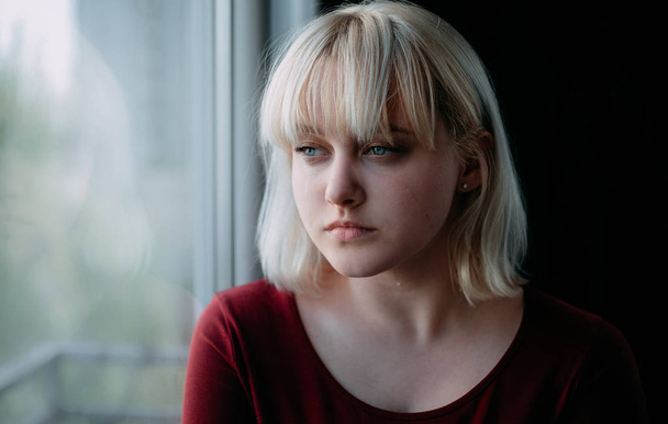 Portrait of sad depressed young woman sitting near window - Фото, зображення