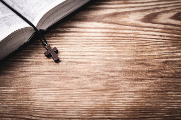 Pismo Święte z drewnianym krzyżem na drewnianym stole. - Zdjęcie, obraz