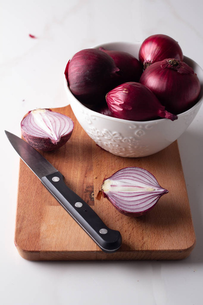 cebolla roja en un plato blanco y tabla de cortar sobre un fondo blanco
 - Foto, Imagen