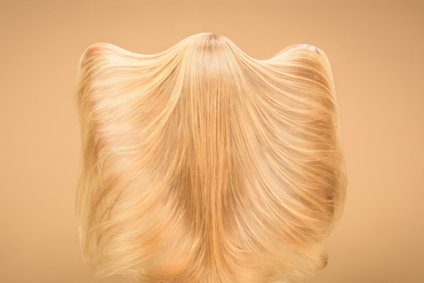 Takaisin näkymä nainen leikkii hänen pitkät hiukset beige tausta
 - Valokuva, kuva