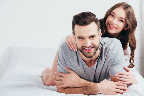 giovane coppia amorevole sorridente e sdraiato su biancheria da letto bianca
 - Foto, immagini