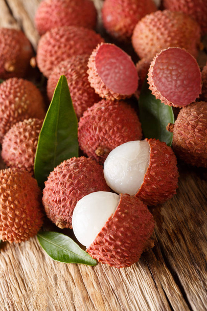 Delicious fresh lychees with green leaves close-up on a wooden table. vertica - Photo, Image