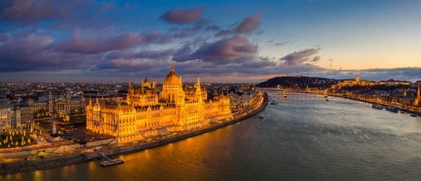 Budapešť, Maďarsko - Letecký panoramatický pohled na krásně osvětlený maďarský parlament s Řetězovým mostem Szechenyi, královským palácem Budínského hradu a barevnými mraky na pozadí při západu slunce - Fotografie, Obrázek