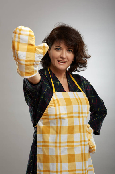 Housewife in apron and cooking gloves, making a stop sign - Фото, изображение
