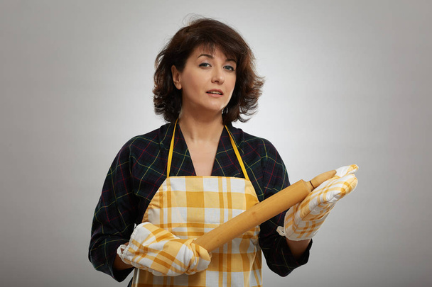 Baker lady with a wooden rolling pin over gray background - Fotó, kép