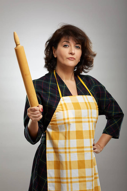 Baker lady with a wooden rolling pin over gray background - Fotoğraf, Görsel