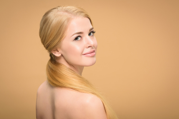 atractiva chica rubia desnuda con el pelo largo sonriendo a la cámara aislada en beige
 - Foto, imagen