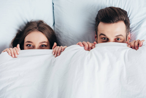 adult couple hiding under blanket in bed  - Фото, зображення
