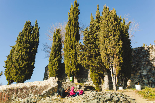 Beraded ember nyugszik a kis lányok közelében fák ciprusok - Fotó, kép