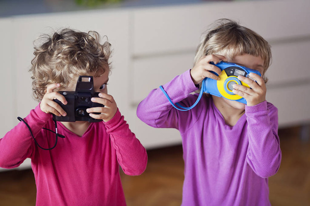 Kaksi pikkulasten tytöt leikkivät kamerat kotona
 - Valokuva, kuva