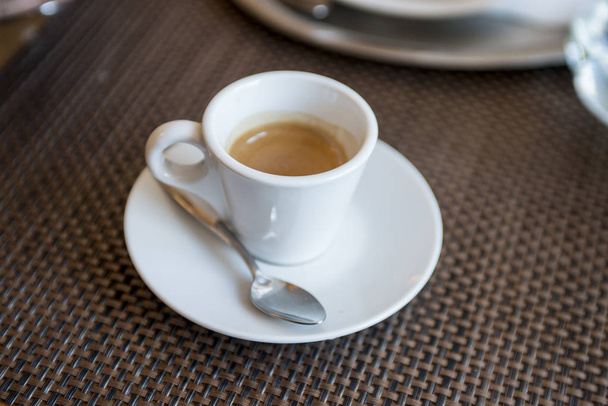 espresso coffee in a white cup on a table in a cafe - 写真・画像